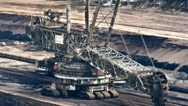 A large bucket-wheel excavator operating in an open-pit coal mine, showing industrial mining machinery and earth excavation.
